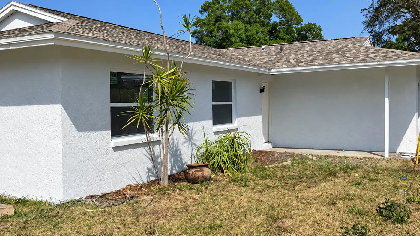 The same stucco house wall painted clean white with the trim cut in