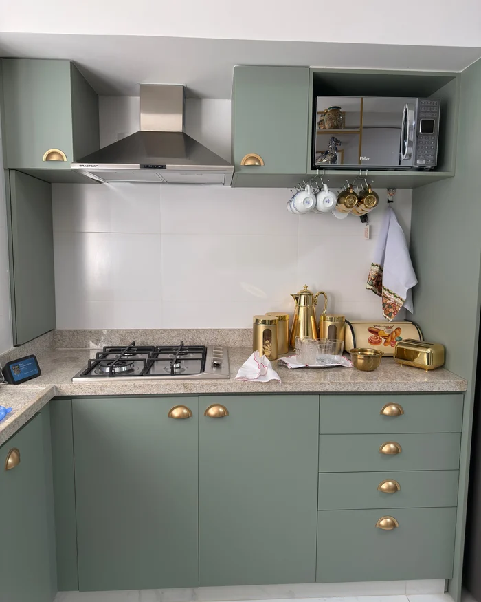 Kitchen cabinets painted a smooth sage green with brass cup pulls